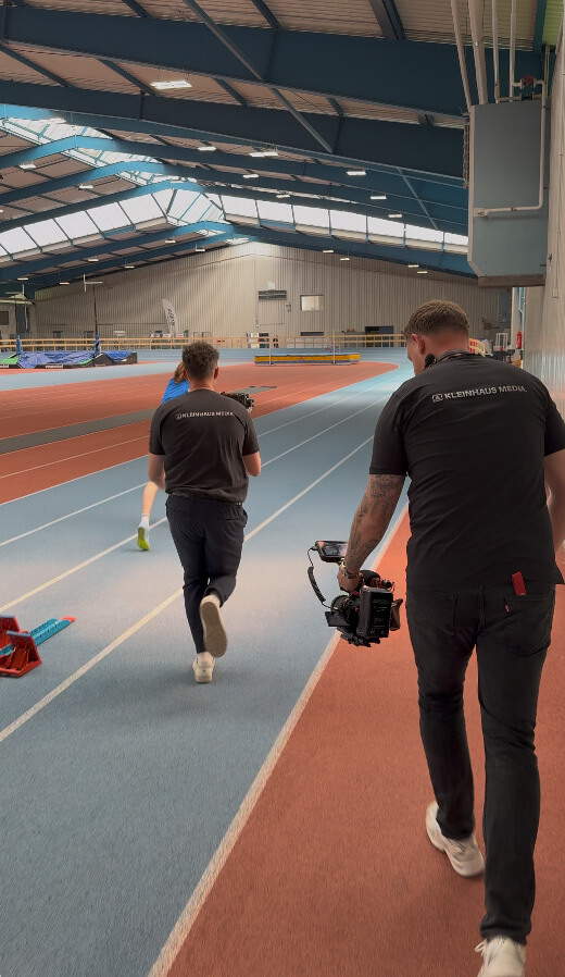 Kamerateam von Kleinhaus Media filmt eine Läuferin in einer Sporthalle für das Imagefilm-Projekt des Instituts für Sportstättenprüfung.