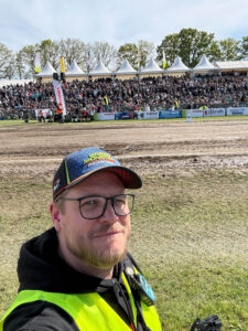 Andreas Duck als Marketing-Verantwortlicher mit Warnweste und Green Monster Cap beim Tractor Pulling Event in Füchtorf vor gut gefüllten Zuschauertribünen.